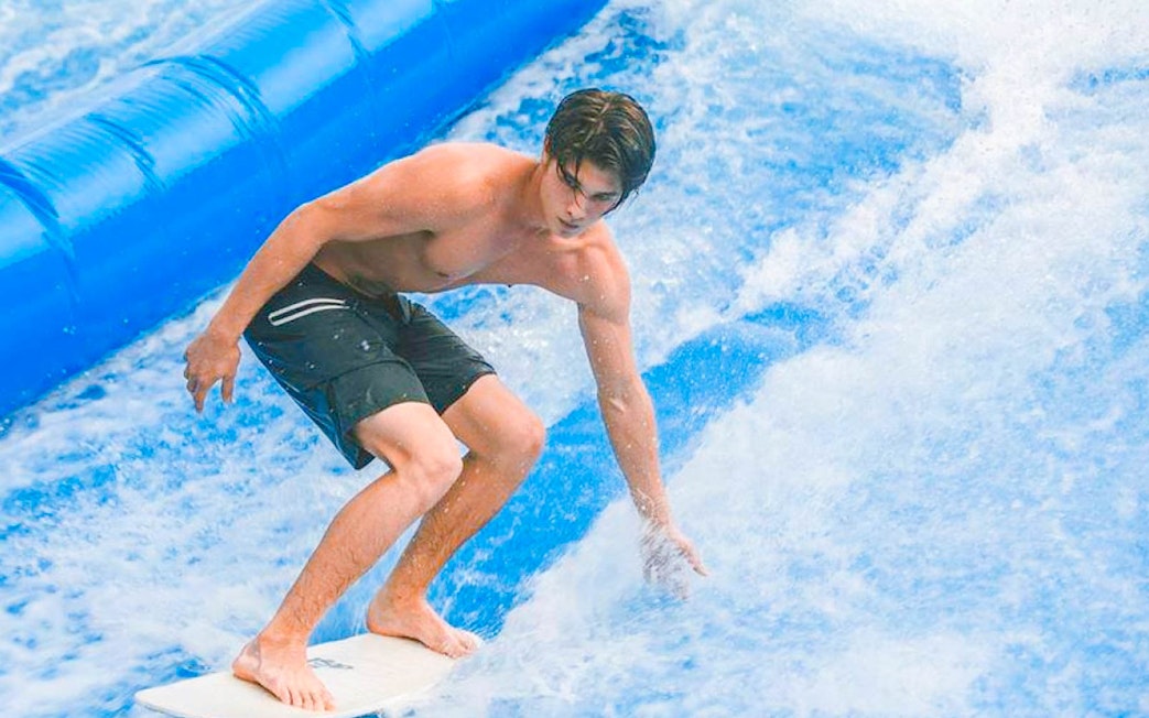 Surfer riding artificial wave at Flow House Bangkok.