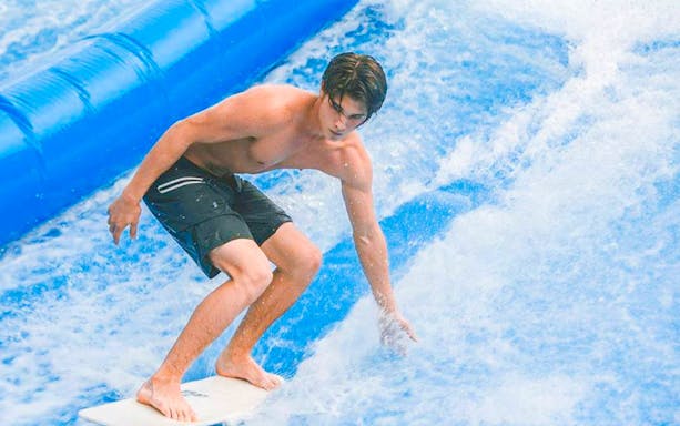 Surfer riding artificial wave at Flow House Bangkok.