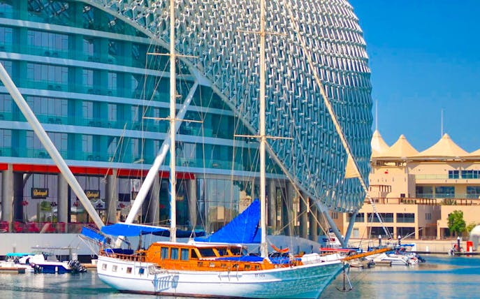 Sailboat docked at Yas Marina with modern architecture in the background.