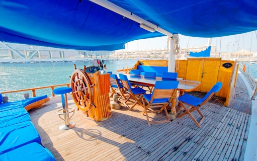 Yas Marina boat deck with wooden steering wheel and seating area.