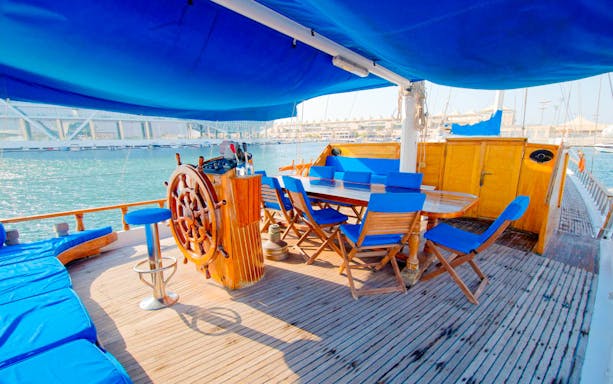 Yas Marina boat deck with wooden steering wheel and seating area.