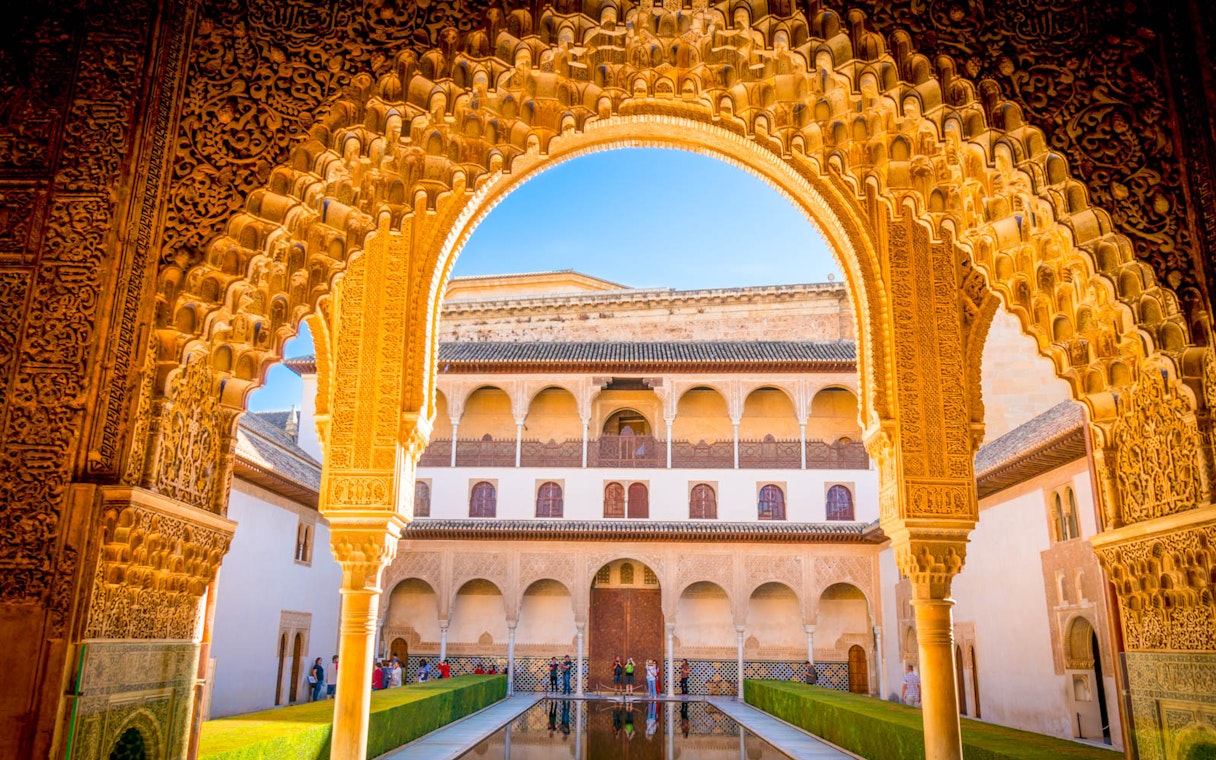 Alhambra's Nasrid Palace courtyard with intricate arch and reflecting pool, Granada, Spain.