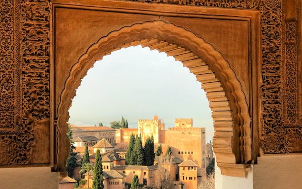 Alhambra view through ornate archway in Granada, Spain.