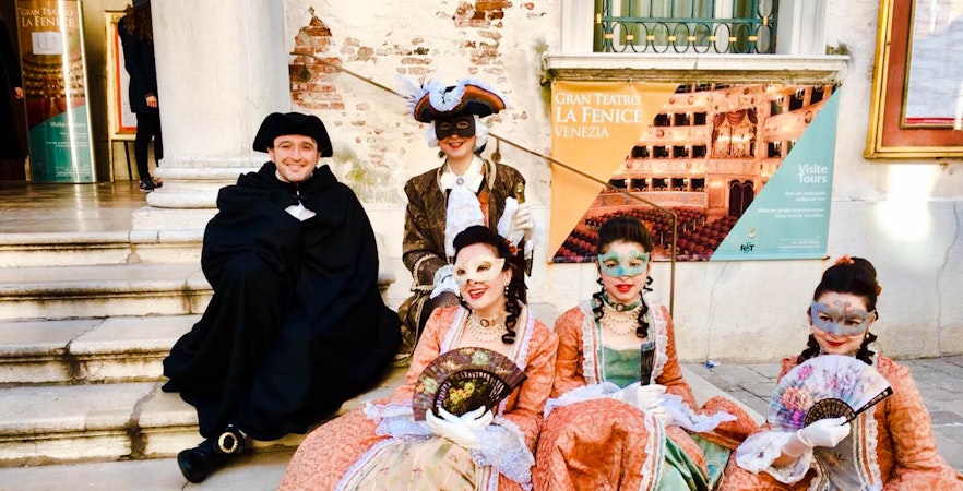 Venice Carnival participants in traditional costumes and masks outside Gran Teatro La Fenice.