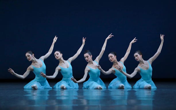 Ballet dancers in blue costumes performing a synchronized pose, inspired by George Balanchine.