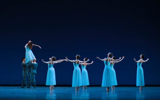 Ballet dancers performing on stage in blue costumes, inspired by George Balanchine choreography.