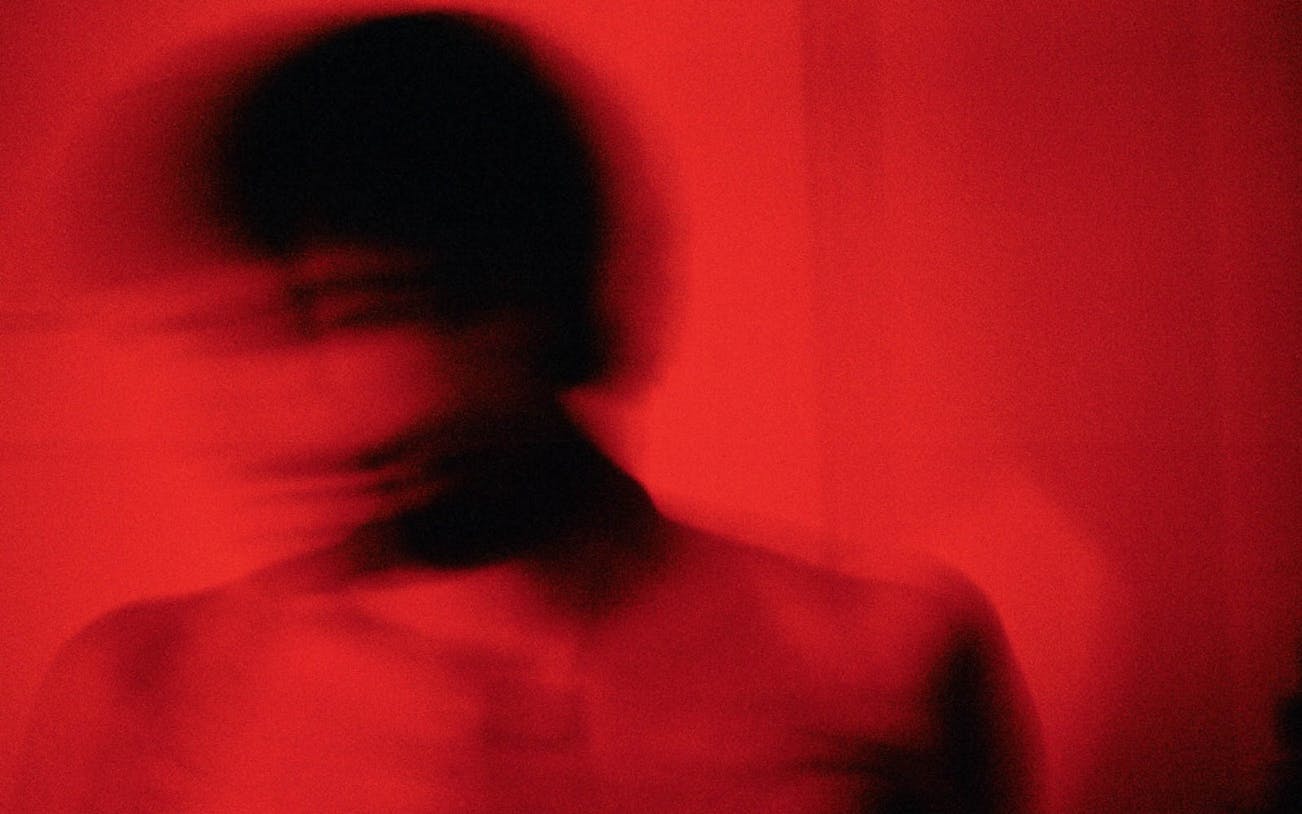 Blurry silhouette in red lighting, Mayerling tour atmosphere.