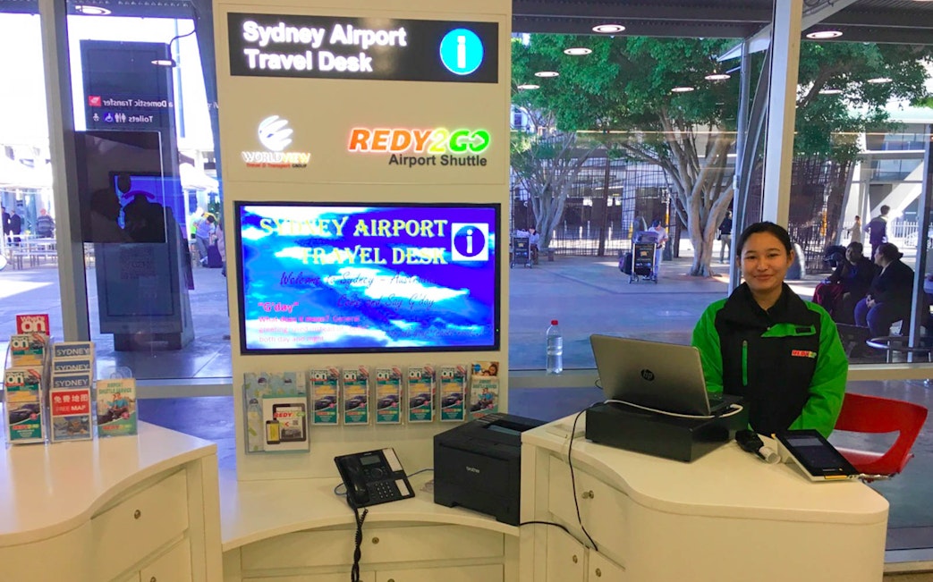 Sydney Airport travel desk with staff for shuttle to city hotels.