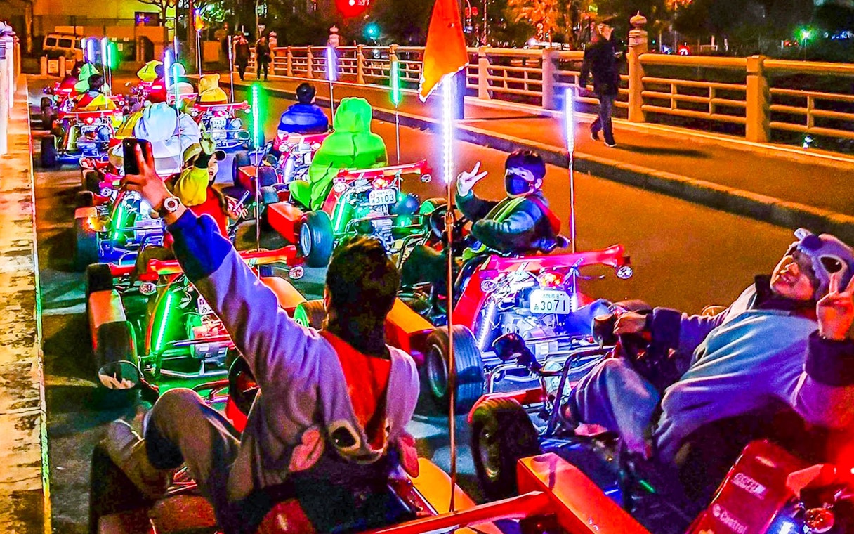 Go-kart riders in costumes on Osaka street during Akiba Kart experience.