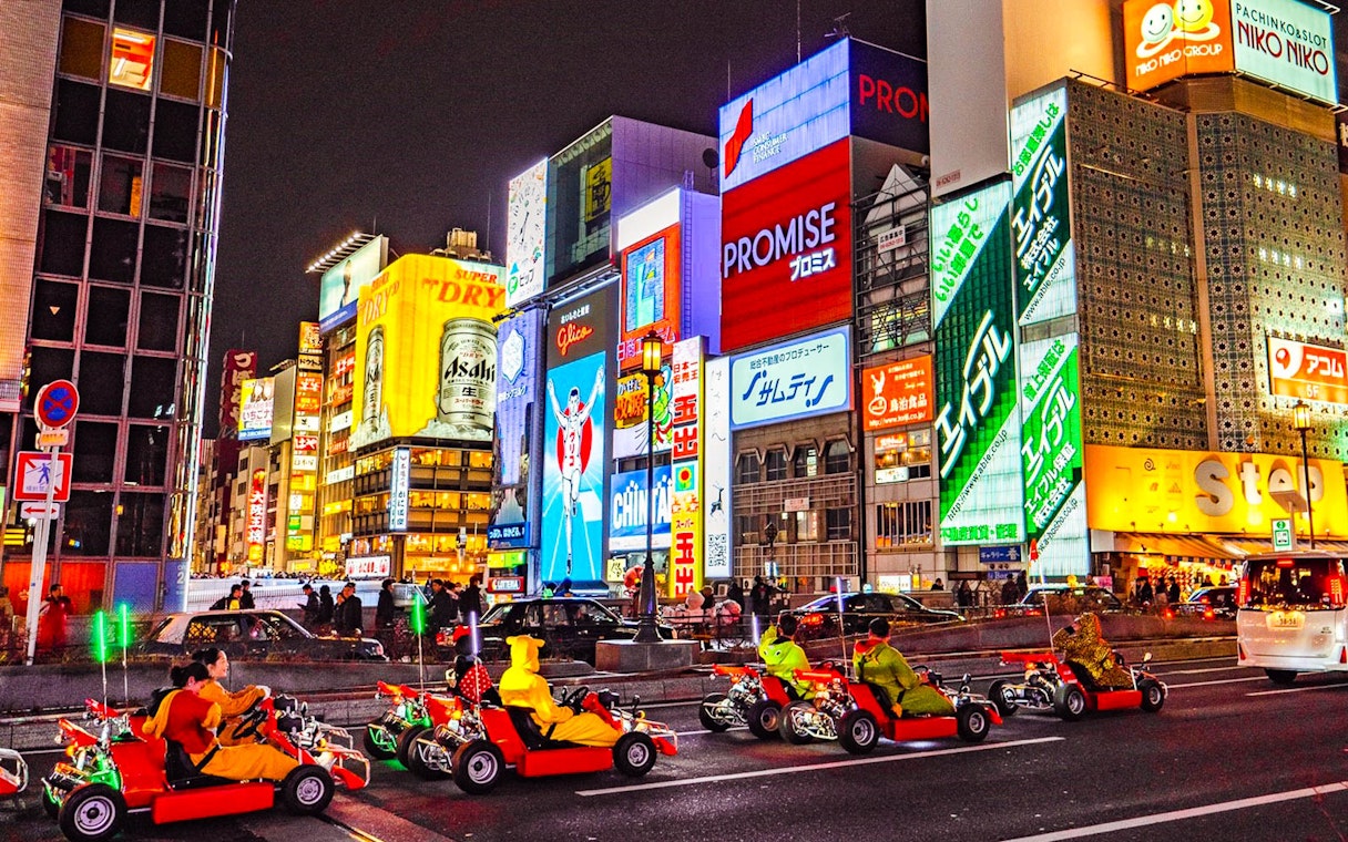 Go-karts driving through illuminated streets of Osaka during Akiba Kart experience.