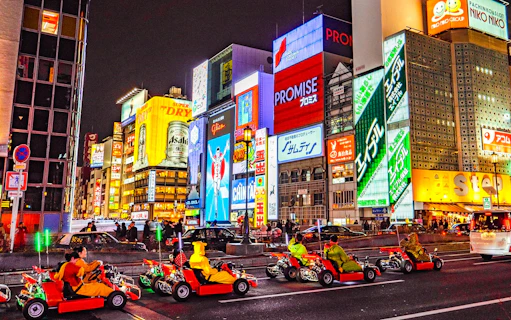 Go-karts driving through illuminated streets of Osaka during Akiba Kart experience.