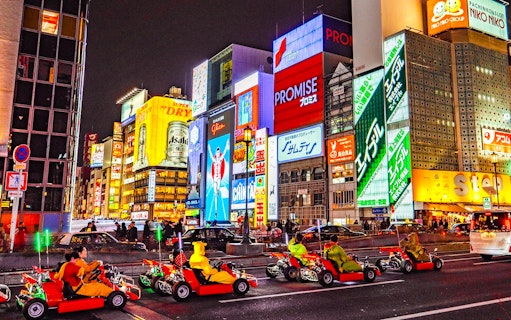 Go-karts driving through illuminated streets of Osaka during Akiba Kart experience.