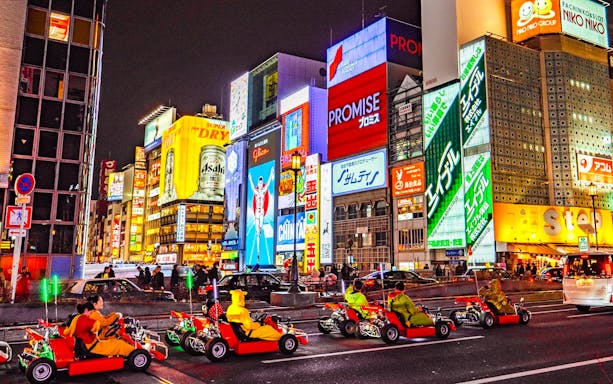 Go-karts driving through illuminated streets of Osaka during Akiba Kart experience.