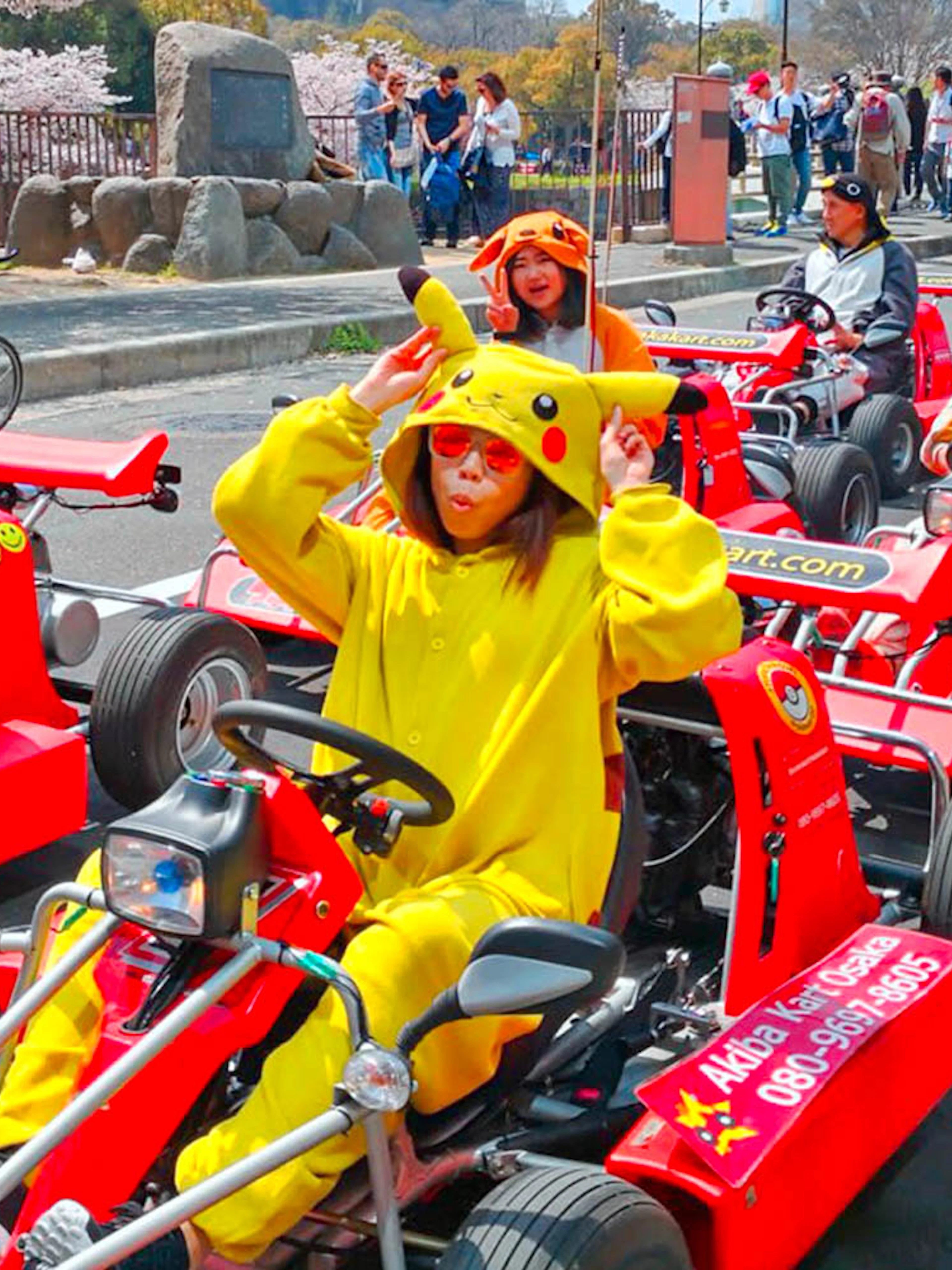 People in character costumes driving go-karts on Osaka street during Akiba Kart experience.
