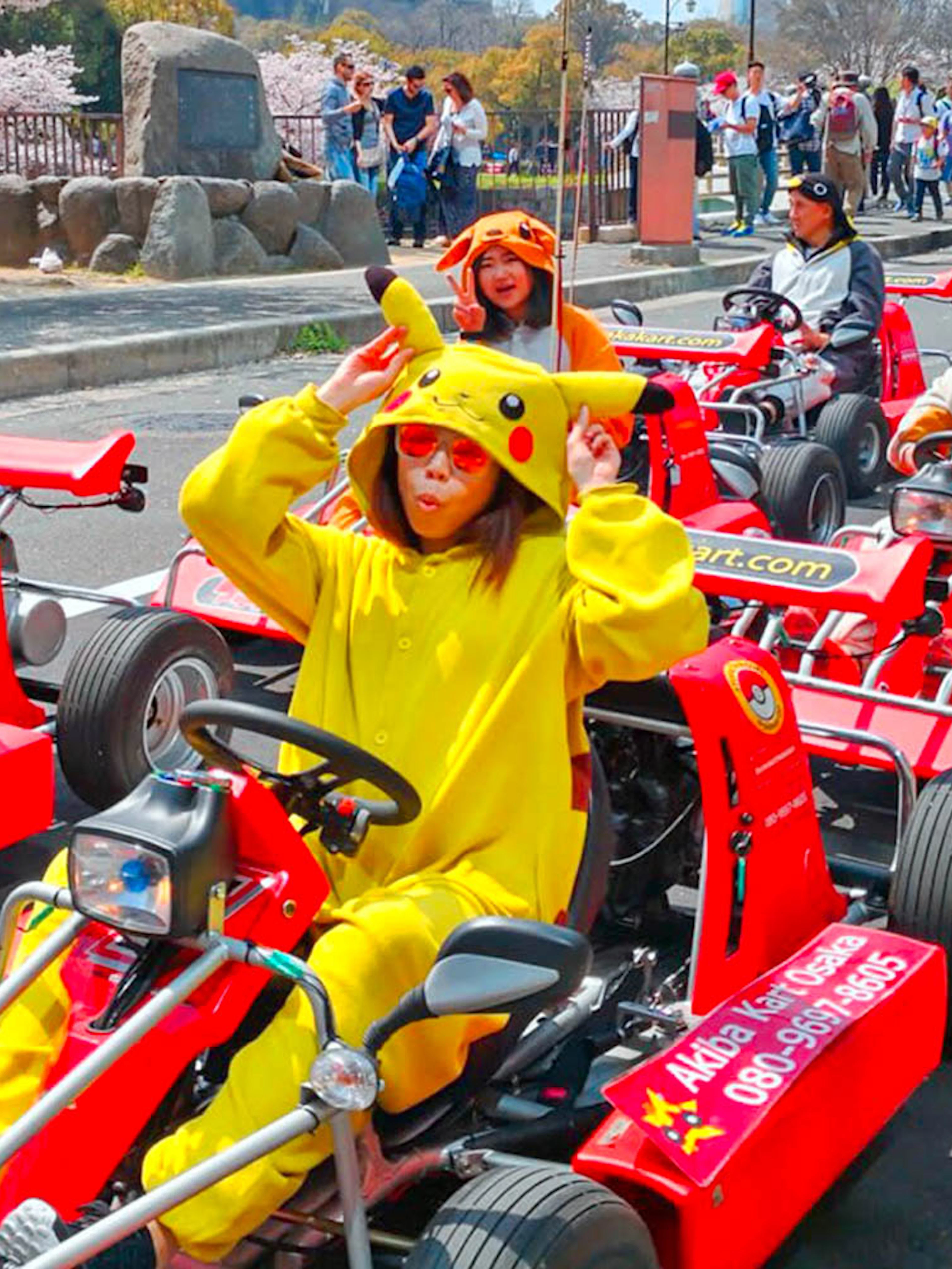People in character costumes driving go-karts on Osaka street during Akiba Kart experience.