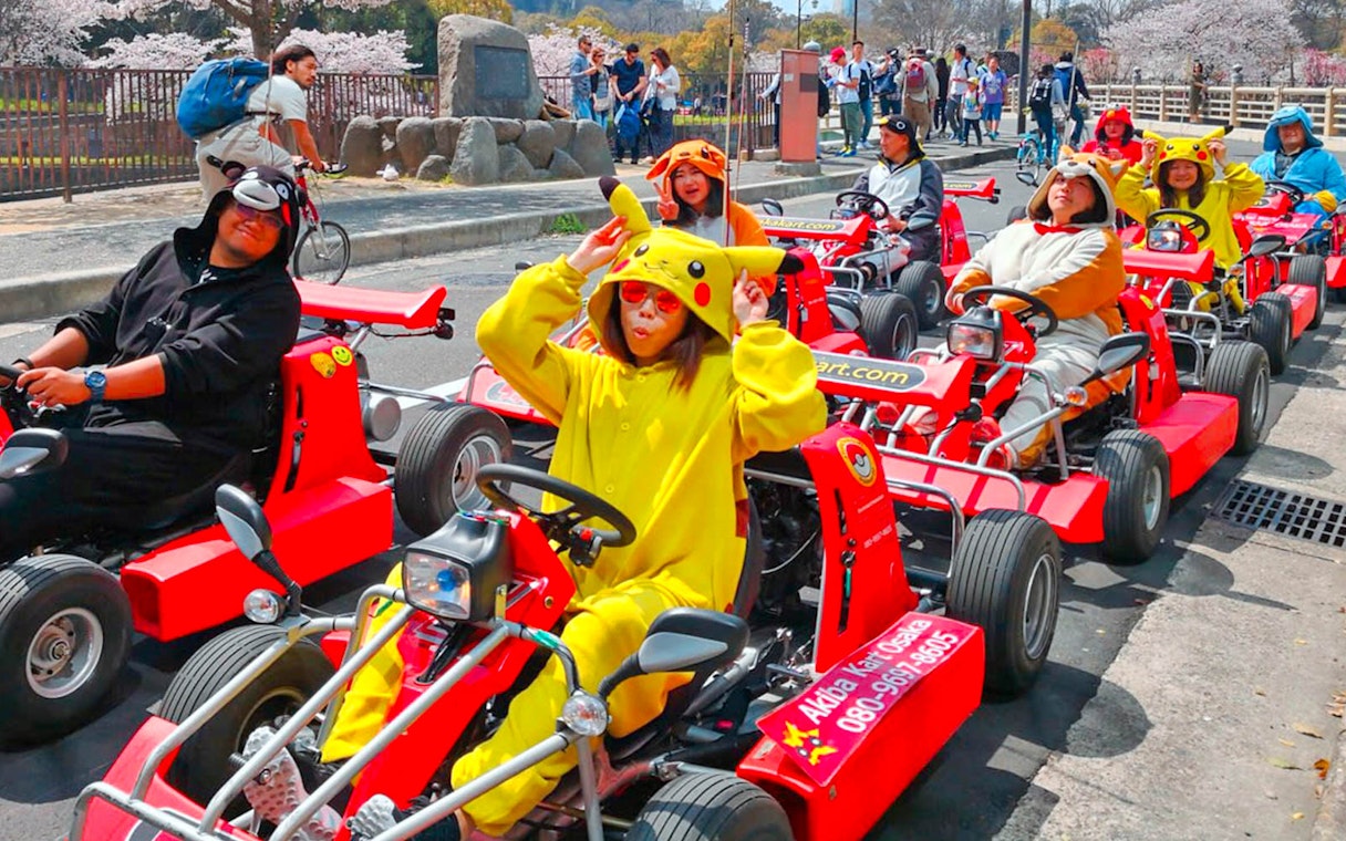 People in character costumes driving go-karts on Osaka street during Akiba Kart experience.