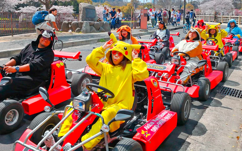 People in character costumes driving go-karts on Osaka street during Akiba Kart experience.