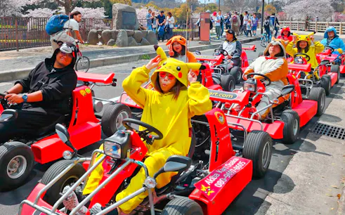 People in character costumes driving go-karts on Osaka street during Akiba Kart experience.
