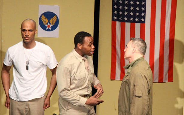 Actors performing a scene from "Black Angels Over Tuskegee" with an American flag backdrop.