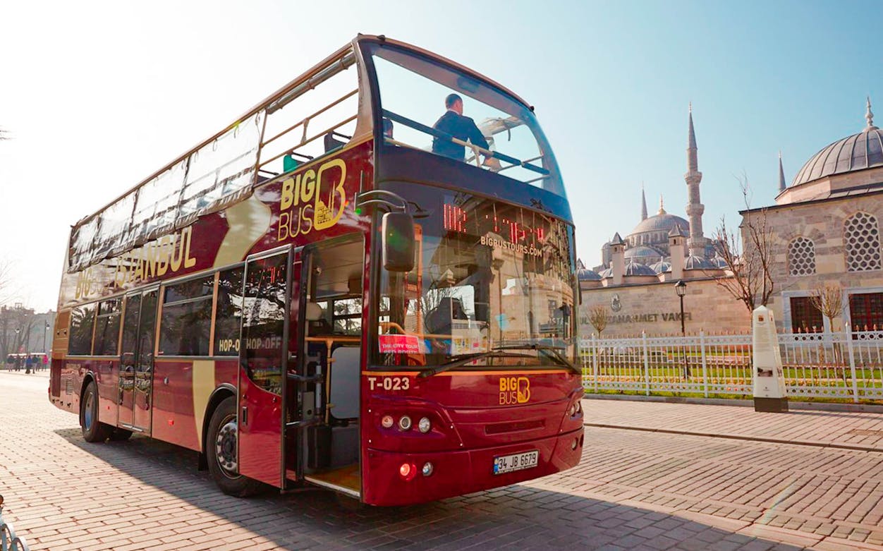 BigBus Istanbul tour bus near historic mosque, offering hop-on-hop-off city sightseeing.