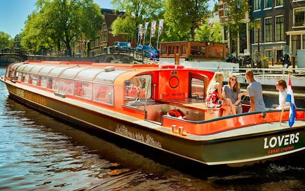 Canal cruise boat with tourists on Amsterdam canal, near Red Light Secrets Museum.
