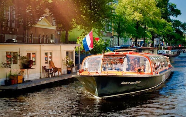 Canal cruise boat on Amsterdam canal near Red Light Secrets Museum.