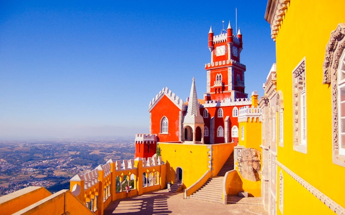 National Palace of Pena in Sintra with vibrant red and yellow towers against a clear sky.