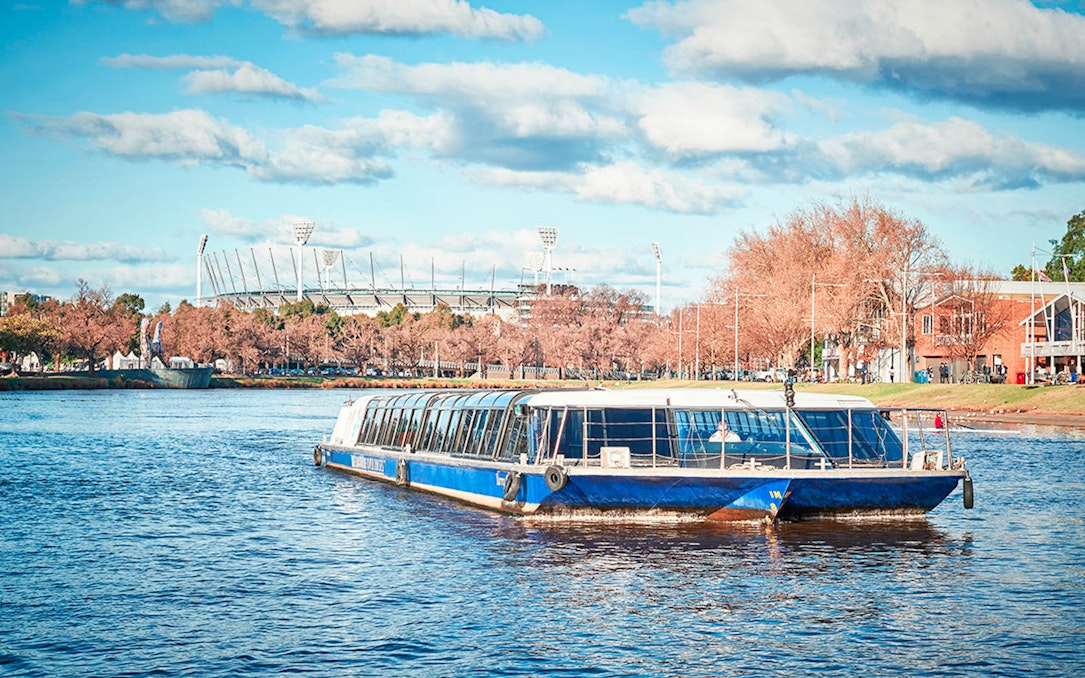 River cruise boat on Yarra River with Melbourne Cricket Ground in background.