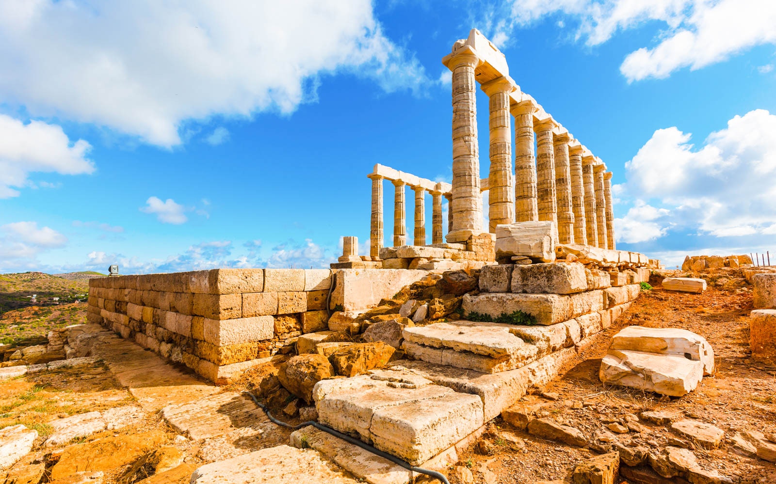 Temple of Poseidon ruins at Cape Sounion under a blue sky, part of guided tour from Athens.