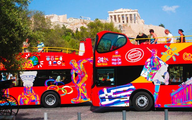 Open-top tour bus in Athens with Acropolis in the background.