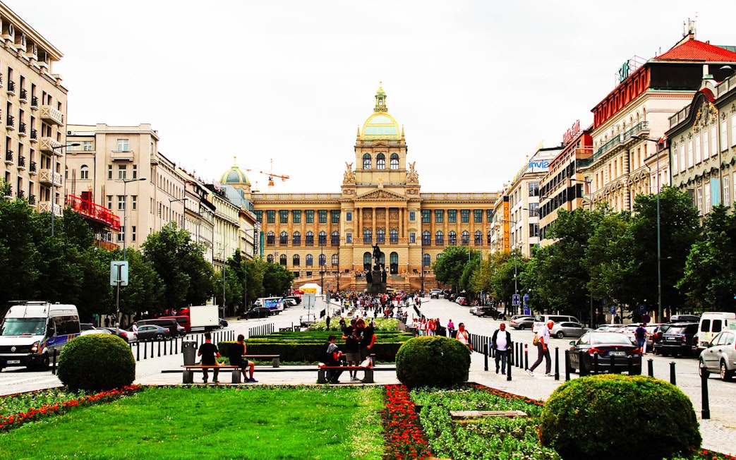 Prague National Museum with bustling street and visitors in front.