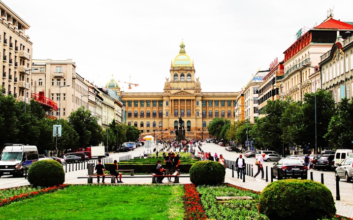 Prague National Museum with bustling street and visitors in front.