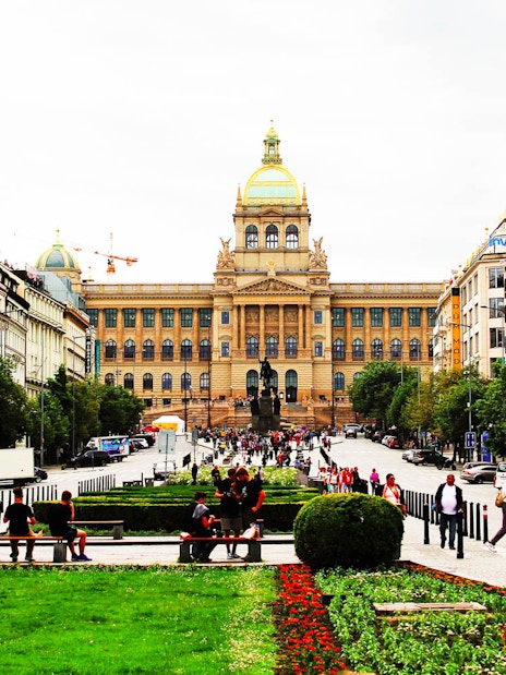 Prague National Museum with bustling street and visitors in front.