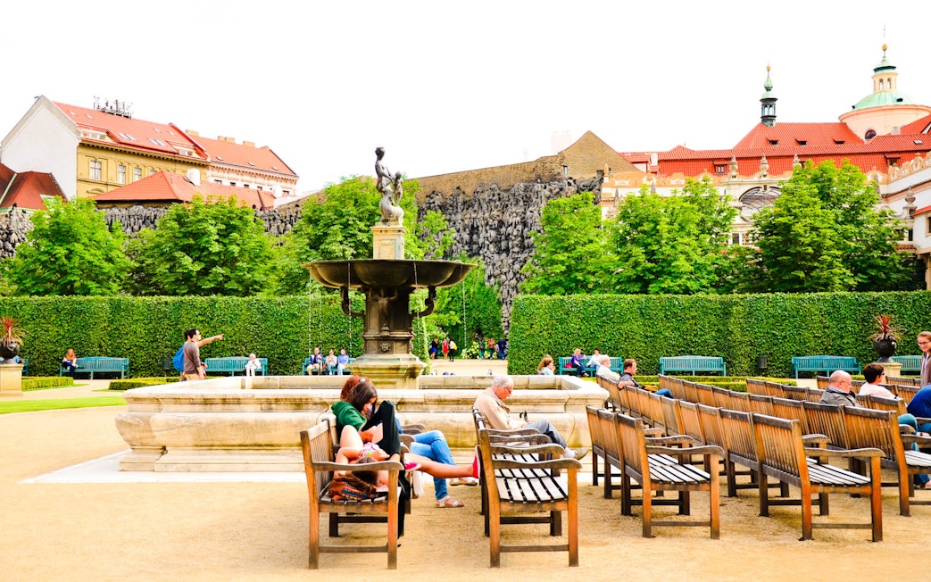 Visitors relaxing by a fountain in the gardens of Prague Castle.