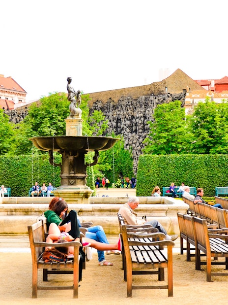 Visitors relaxing by a fountain in the gardens of Prague Castle.