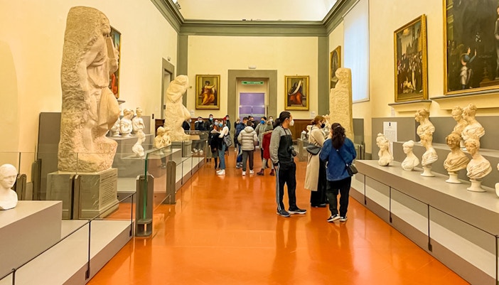 Visitors viewing sculptures and paintings in a gallery at Palazzo Pitti, Florence.