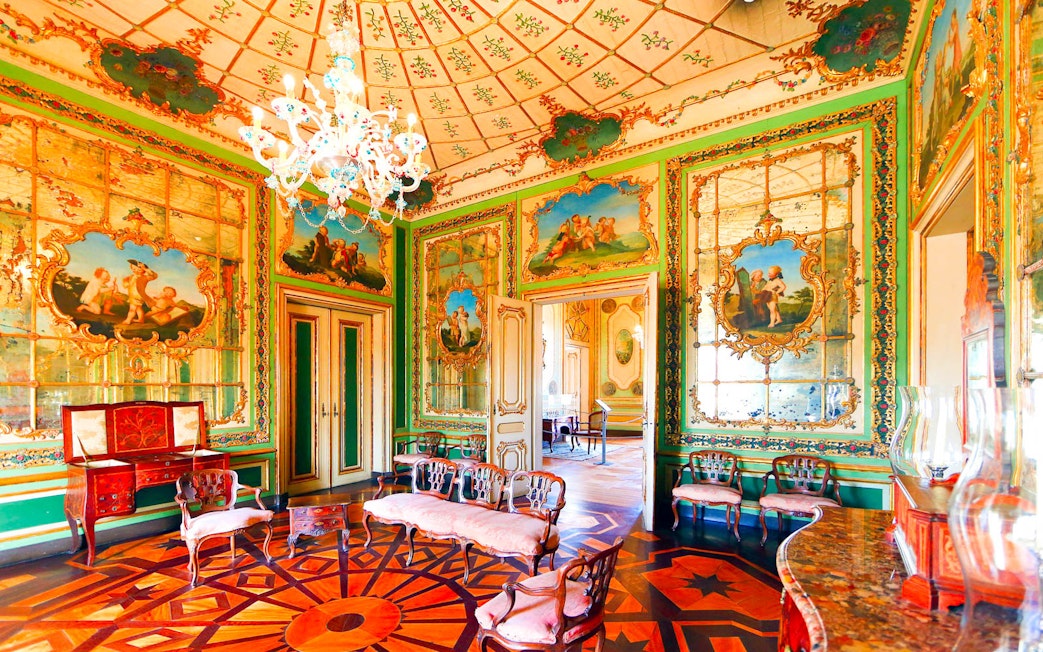 Ornate room in the National Palace of Queluz with detailed frescoes and elegant furniture.