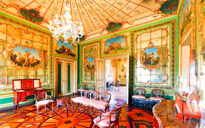 Ornate room in the National Palace of Queluz with detailed frescoes and elegant furniture.