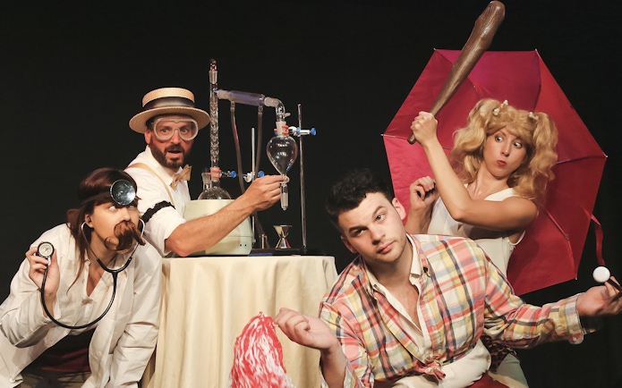 Performers in a comedic scene from The Imbible: A Spirited History of Drinking, featuring lab equipment.