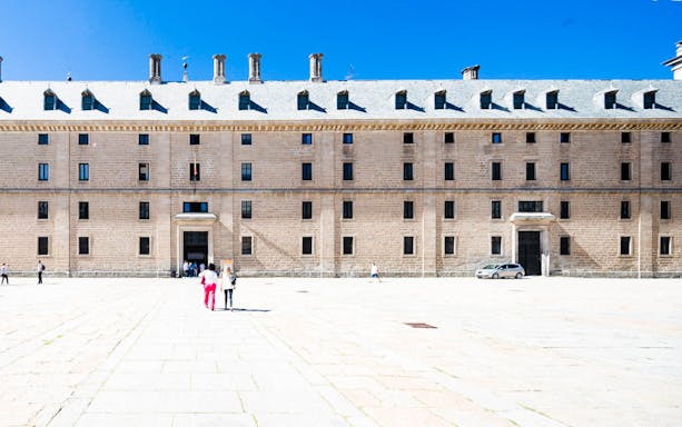 Visitors approaching the Royal Monastery of El Escorial facade on a guided tour.