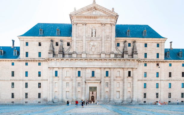 Royal Monastery of El Escorial facade with visitors in courtyard, Spain.
