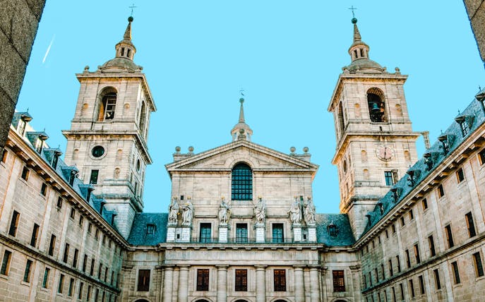 Royal Monastery of El Escorial facade with twin towers and statues, Spain.