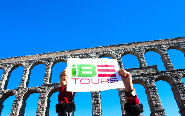 Segovia Aqueduct with tour sign held up during Toledo and Segovia guided tour.