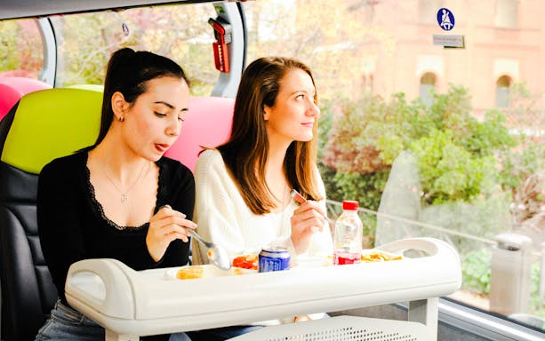 Two women enjoying lunch on a bus during Toledo and Segovia guided tour.