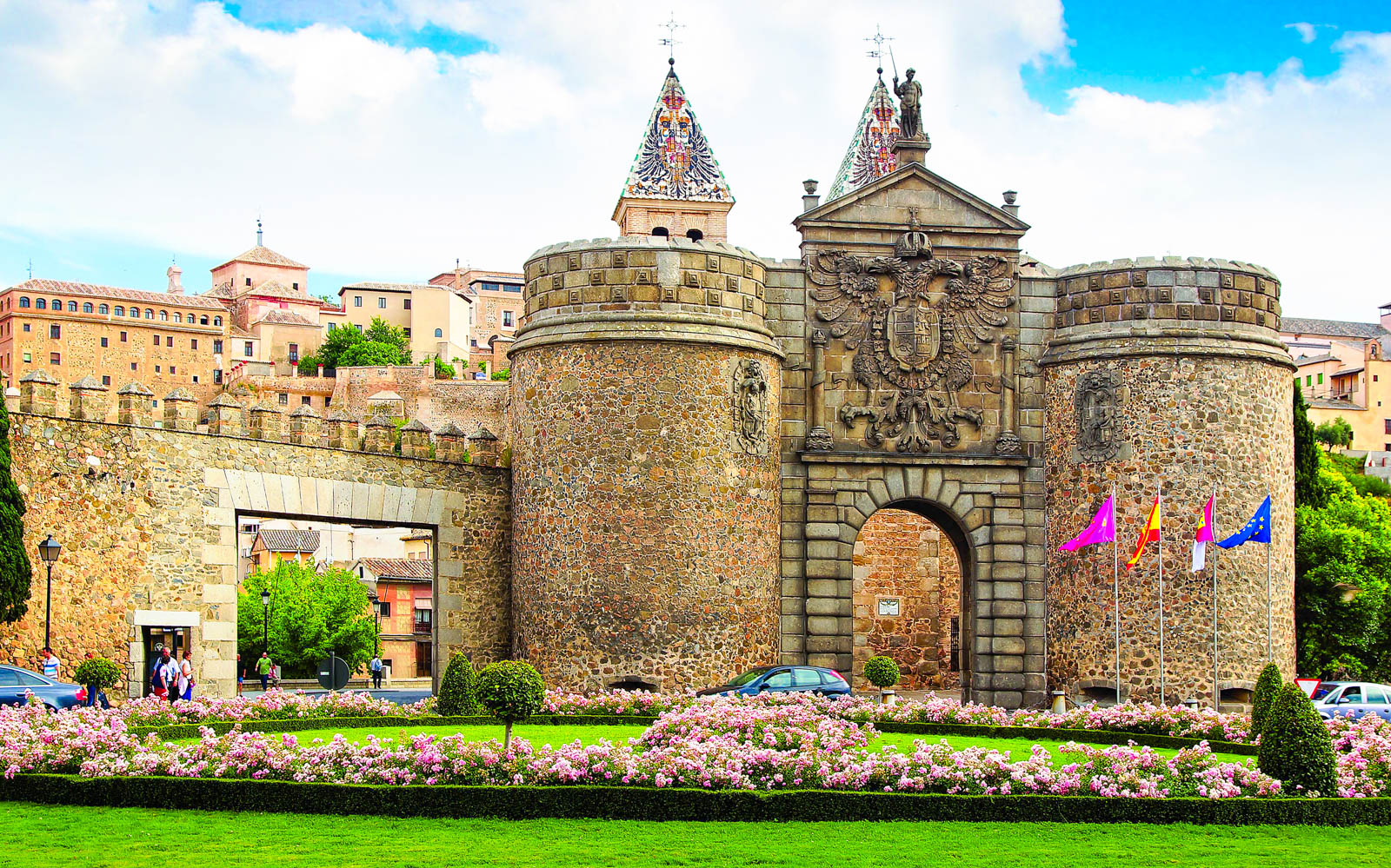 Medieval gate in Toledo with stone towers and flags, part of Segovia, Ávila & Toledo tour.
