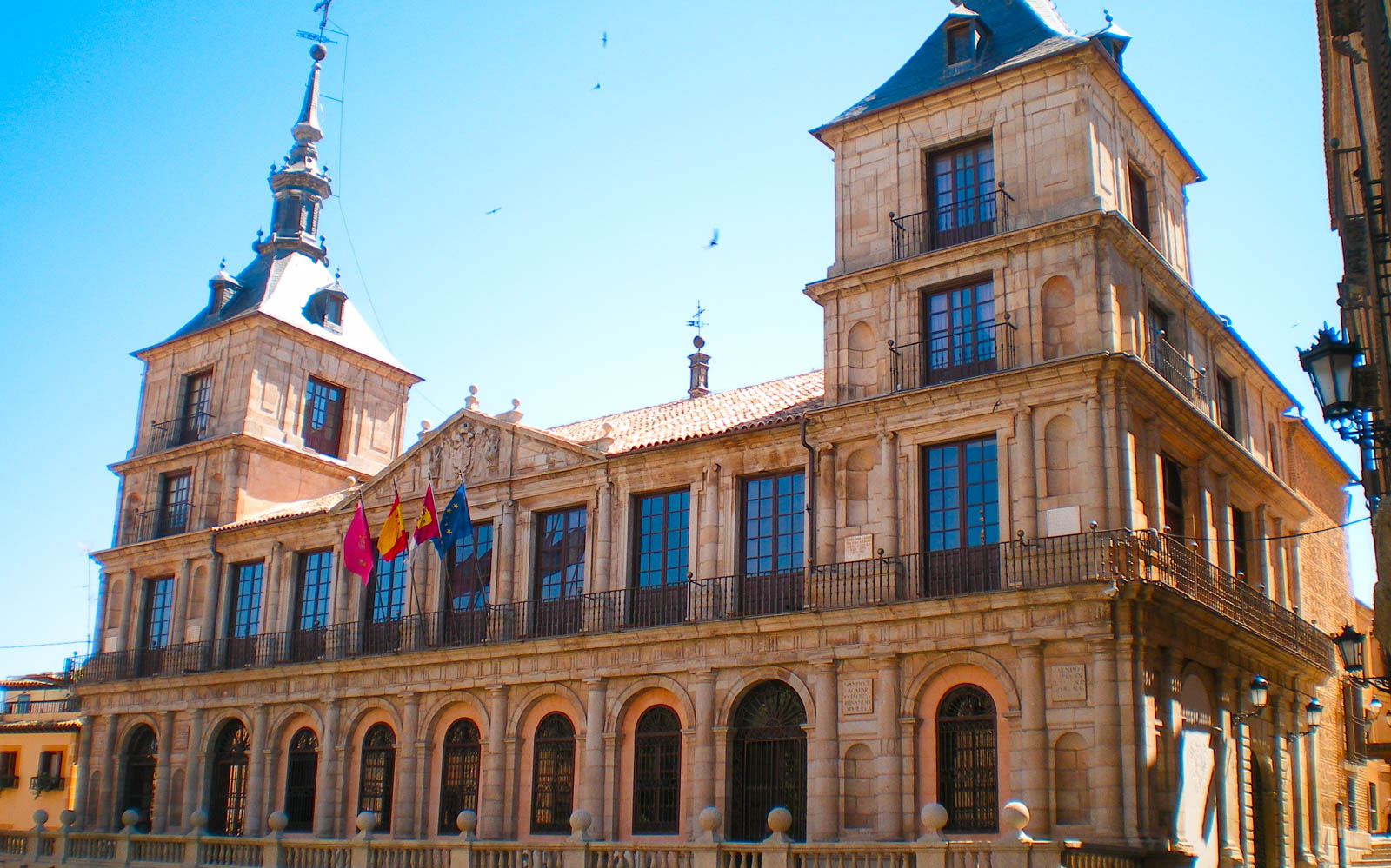 Historic building with flags in Toledo, part of the Segovia, Ávila & Toledo guided tour from Madrid.