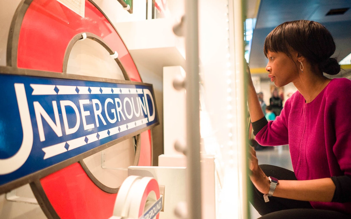 Person examining London Underground sign at London Transport Museum.