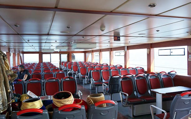 Interior seating of a boat for a 2-hour Bosphorus tour, with red chairs and large windows.