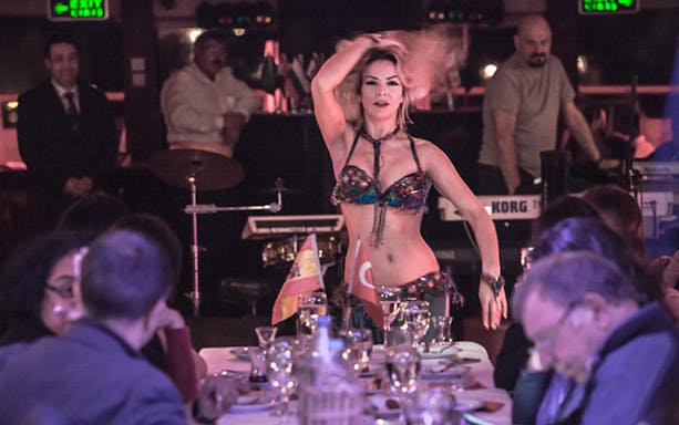 Belly dancer performing on Bosphorus dinner cruise with live band and guests.