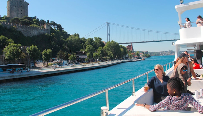 Bosphorus lunch cruise ship sailing near Istanbul's historic skyline with passengers dining.
